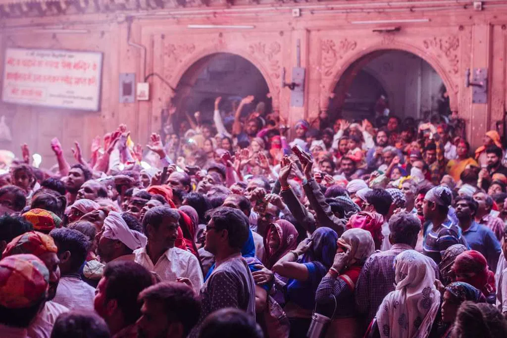 Holi at Banke Bihari Temple — the crowd inside the temple with pink and purple colors filling the air
